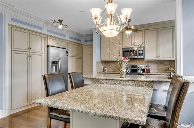 800 W Ferry St Unit 2Cc, Buffalo, NY 14222 - kitchen with stainless steel appliances, a breakfast bar area, tasteful backsplash, a chandelier, and light stone countertops
