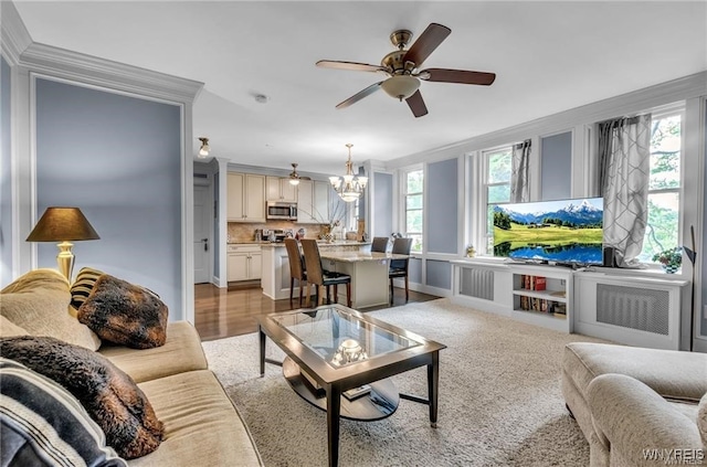 living room featuring crown molding, ceiling fan with notable chandelier, and light hardwood / wood-style floors