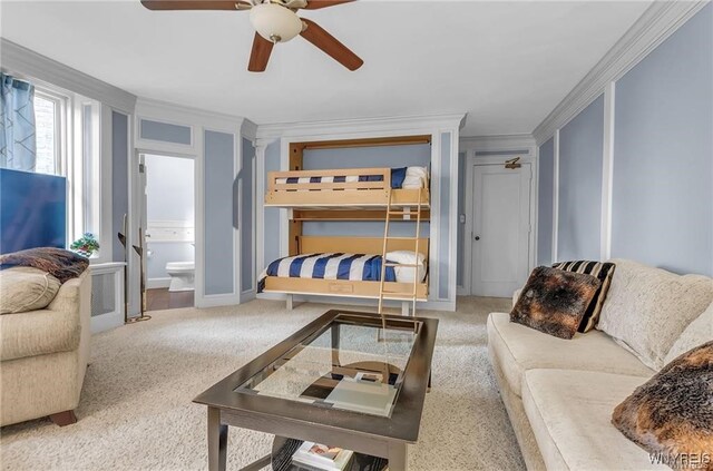 bedroom featuring carpet floors, ornamental molding, ensuite bath, and ceiling fan