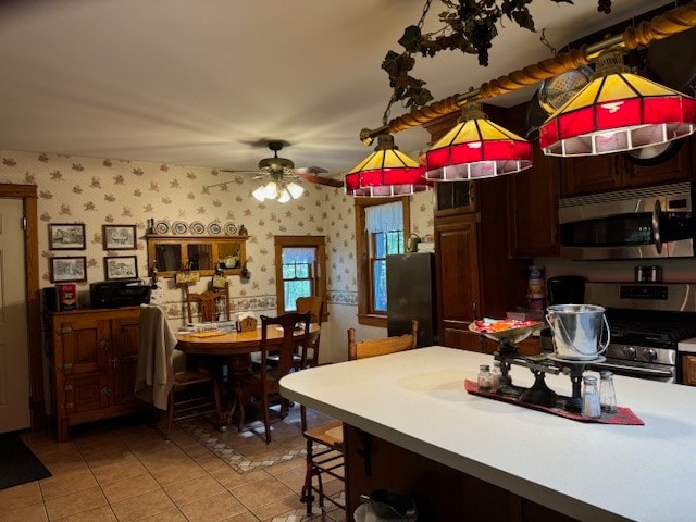 kitchen with a breakfast bar area, dark brown cabinets, light tile patterned flooring, appliances with stainless steel finishes, and ceiling fan