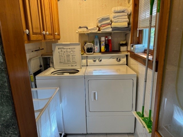 clothes washing area with washer and clothes dryer and cabinets