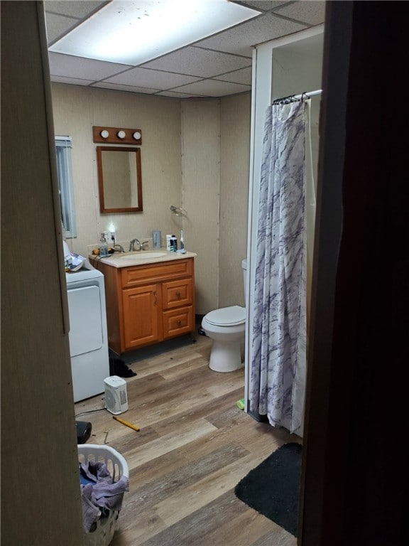 bathroom featuring hardwood / wood-style flooring, toilet, washer / clothes dryer, a drop ceiling, and vanity