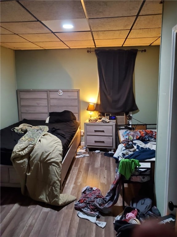 bedroom with a drop ceiling and wood-type flooring