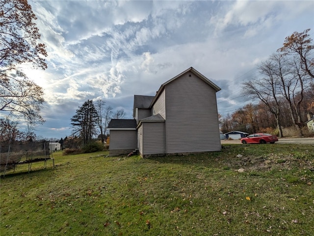 view of home's exterior with a lawn and a trampoline