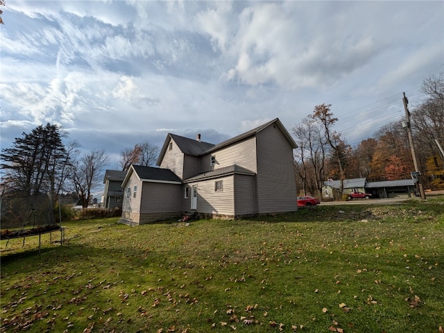 view of side of home with a lawn and a trampoline