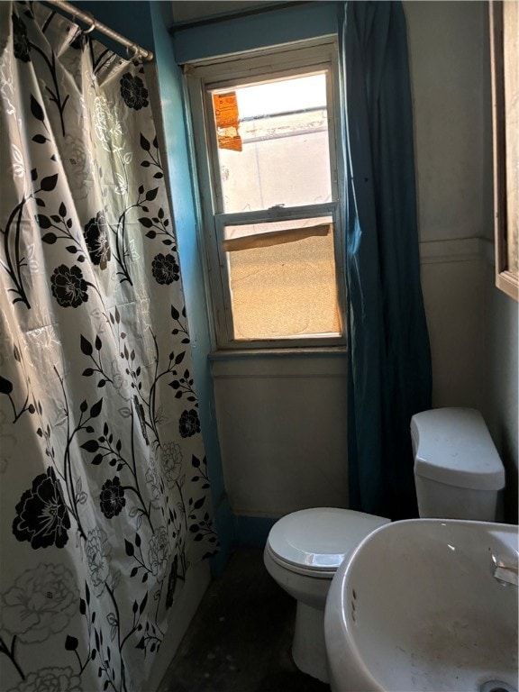 bathroom featuring a shower with shower curtain, plenty of natural light, and toilet