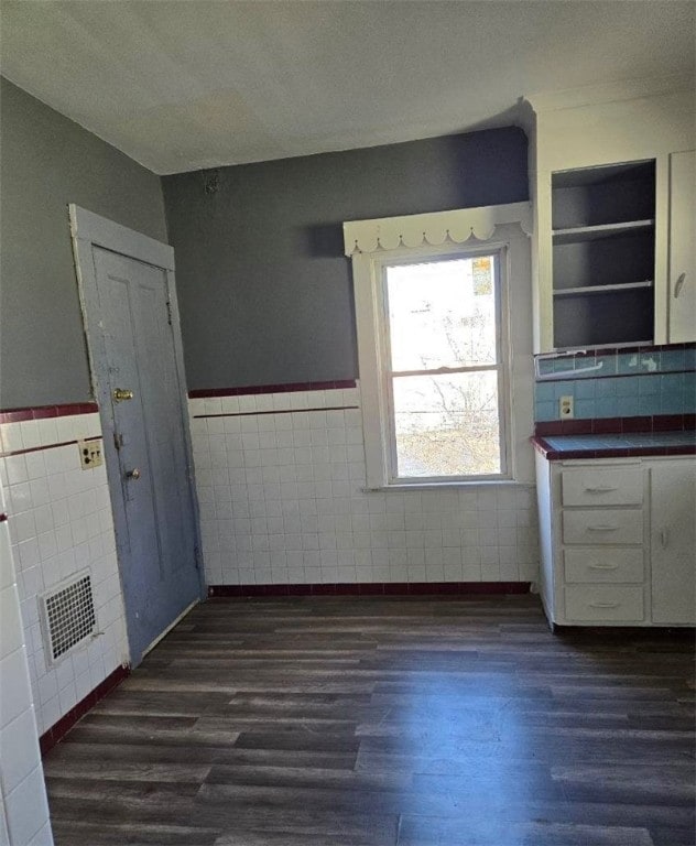 kitchen with white cabinets, dark hardwood / wood-style floors, and tile walls