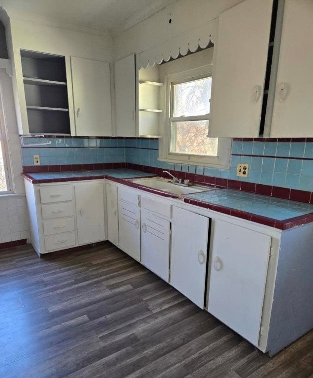 kitchen with dark wood-type flooring, sink, tasteful backsplash, tile counters, and white cabinetry