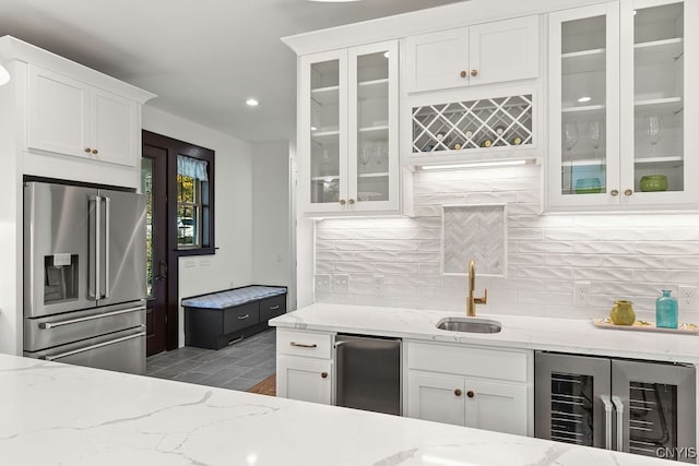 kitchen with white cabinets, sink, wine cooler, stainless steel fridge, and light stone countertops