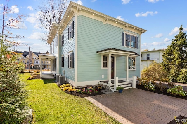 rear view of property with central AC and a lawn