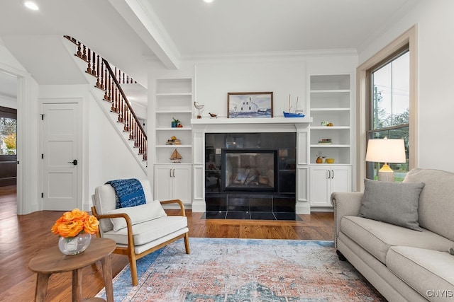 living room with crown molding, dark wood-type flooring, and a tile fireplace