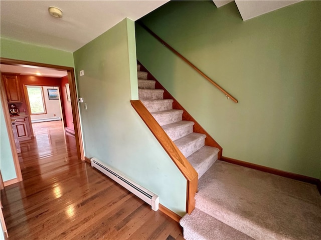 stairs featuring baseboard heating and hardwood / wood-style floors