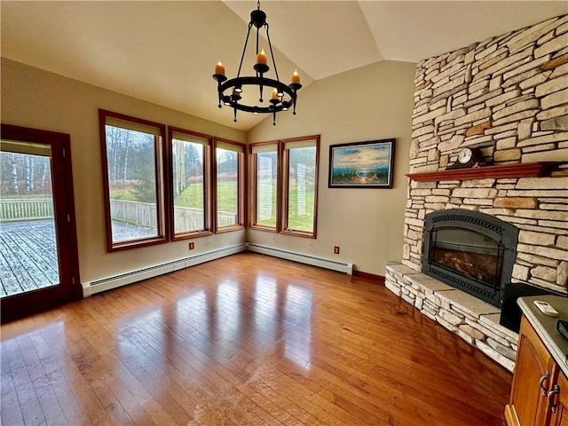 unfurnished living room with light hardwood / wood-style flooring, a notable chandelier, a fireplace, and vaulted ceiling