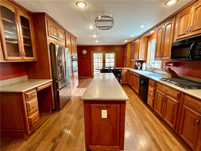 kitchen featuring a kitchen island, french doors, sink, black appliances, and light wood-type flooring