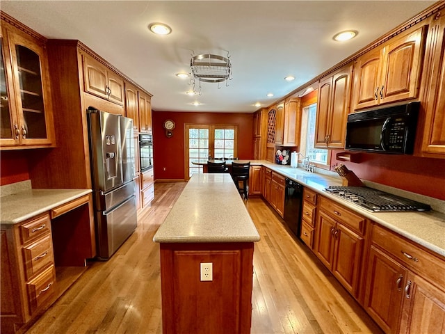 kitchen featuring black appliances, sink, a kitchen island, kitchen peninsula, and light hardwood / wood-style floors