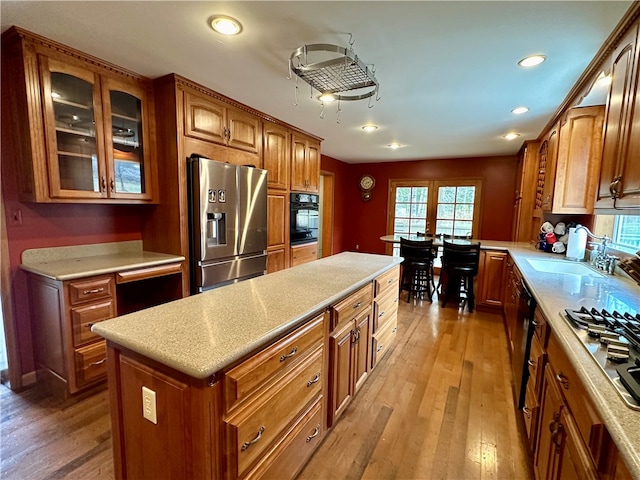 kitchen with sink, a center island, stainless steel appliances, and light wood-type flooring