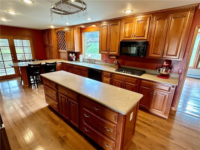 kitchen featuring sink, black appliances, light hardwood / wood-style flooring, and baseboard heating