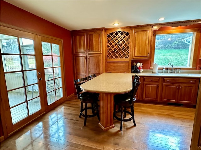 bar with sink, french doors, and light hardwood / wood-style flooring