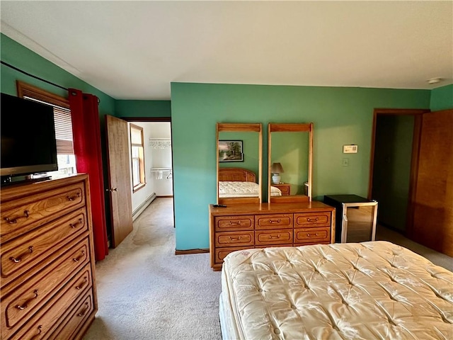 bedroom featuring light carpet, baseboards, and a baseboard heating unit