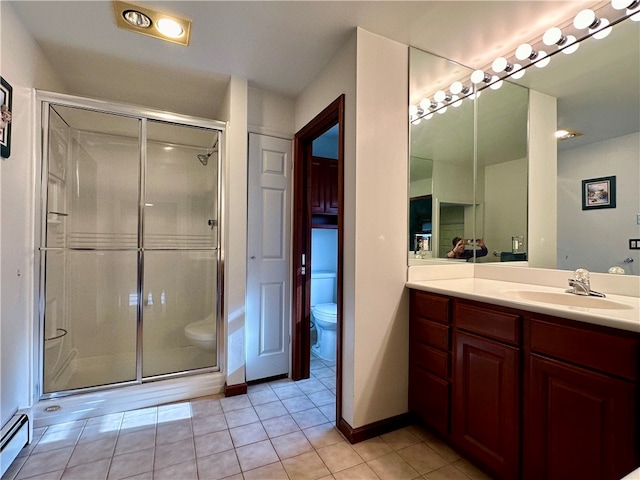 bathroom featuring toilet, a shower with shower door, vanity, and tile patterned floors