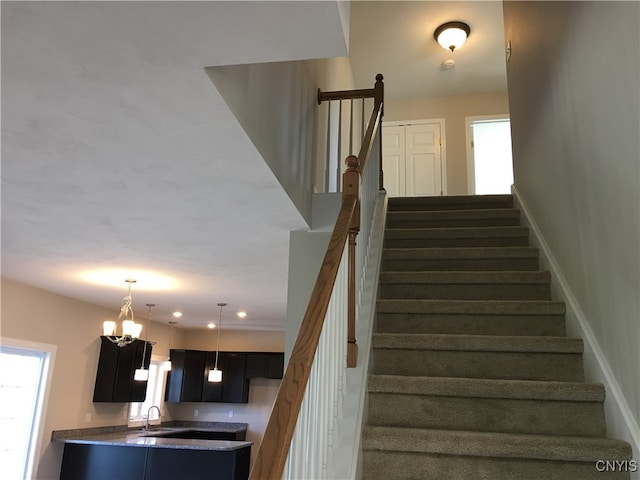 stairs with sink and a chandelier