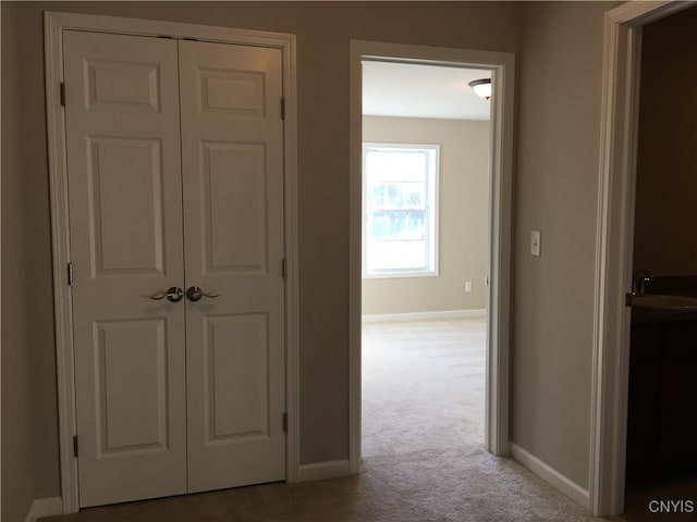 hallway with sink and light carpet