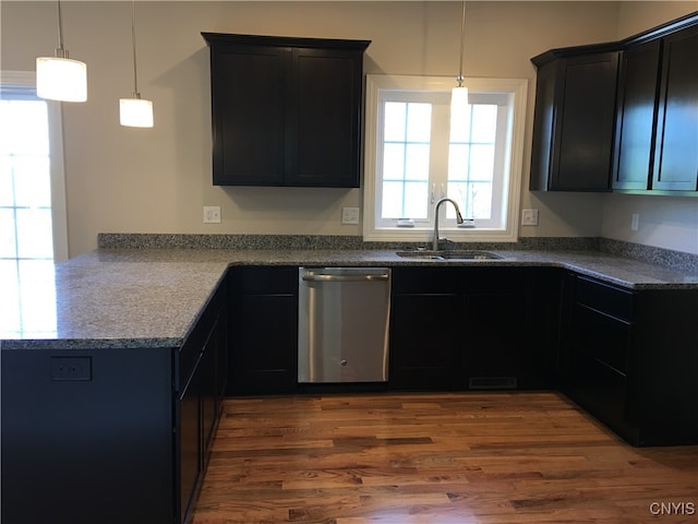 kitchen featuring hanging light fixtures, wood-type flooring, dishwasher, stone countertops, and sink