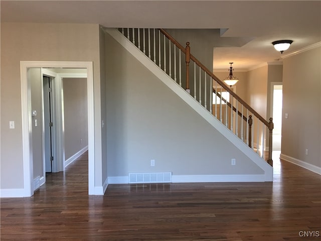 staircase with ornamental molding and hardwood / wood-style floors