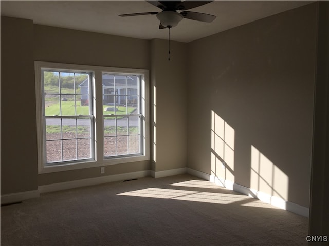 empty room with light carpet, a wealth of natural light, and ceiling fan