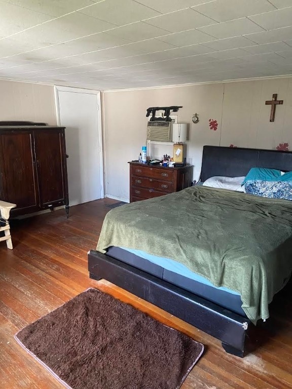 bedroom with ornamental molding and dark hardwood / wood-style floors