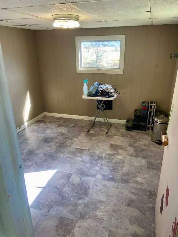 empty room with a paneled ceiling and wood walls