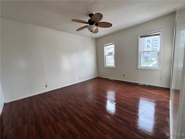 spare room featuring plenty of natural light, a textured ceiling, ceiling fan, and dark hardwood / wood-style flooring