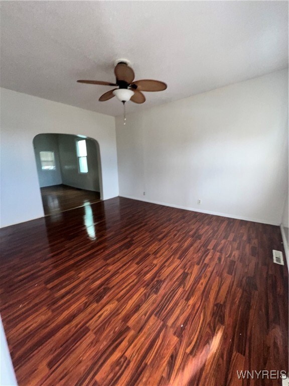 empty room featuring dark wood-type flooring and ceiling fan