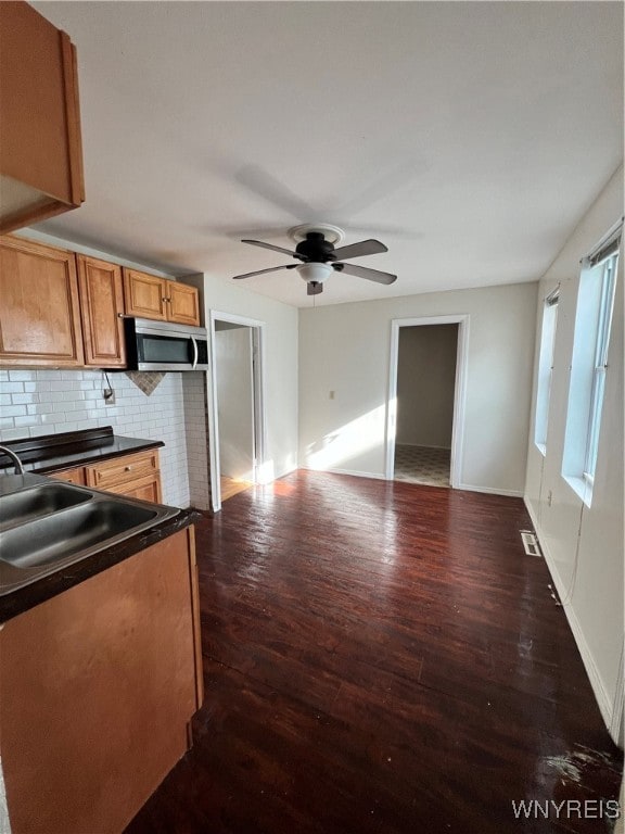 kitchen featuring dark hardwood / wood-style floors, sink, backsplash, and ceiling fan