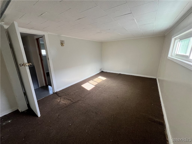 empty room with crown molding and dark carpet