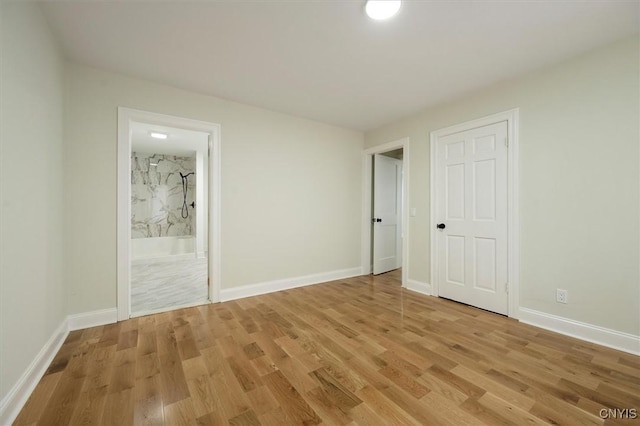 unfurnished bedroom with ensuite bathroom and light hardwood / wood-style flooring