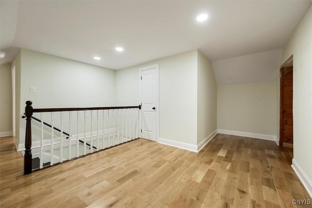 additional living space with vaulted ceiling and light wood-type flooring