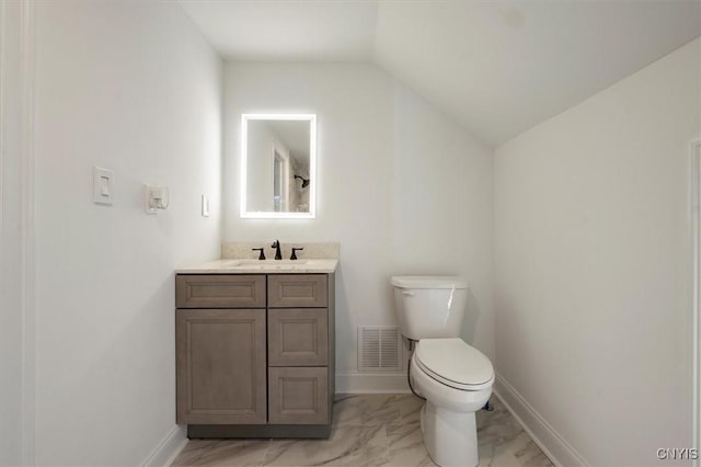 bathroom with toilet, vanity, and vaulted ceiling