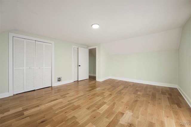 unfurnished bedroom featuring light wood-type flooring and lofted ceiling