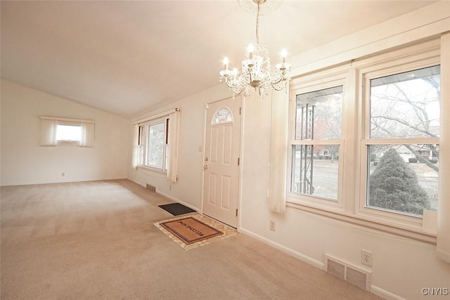 entrance foyer featuring carpet, lofted ceiling, and an inviting chandelier