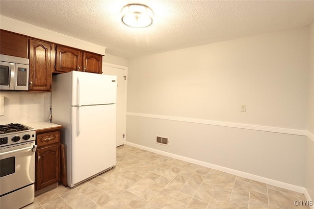 kitchen featuring white refrigerator, a textured ceiling, and gas stove