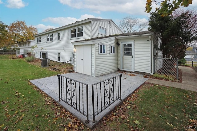 back of property with a lawn, central air condition unit, and a patio