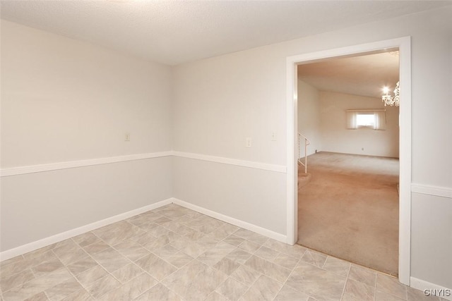 carpeted spare room featuring vaulted ceiling and a notable chandelier