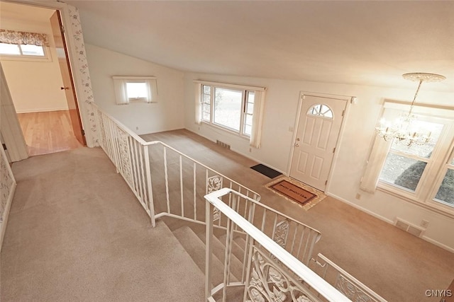 entrance foyer featuring a notable chandelier, light carpet, and vaulted ceiling