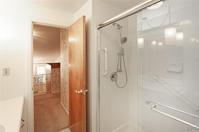 bathroom featuring vanity, a shower with shower door, and tile walls