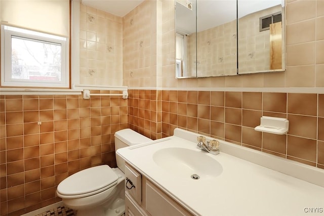 bathroom with vanity, tile walls, and toilet