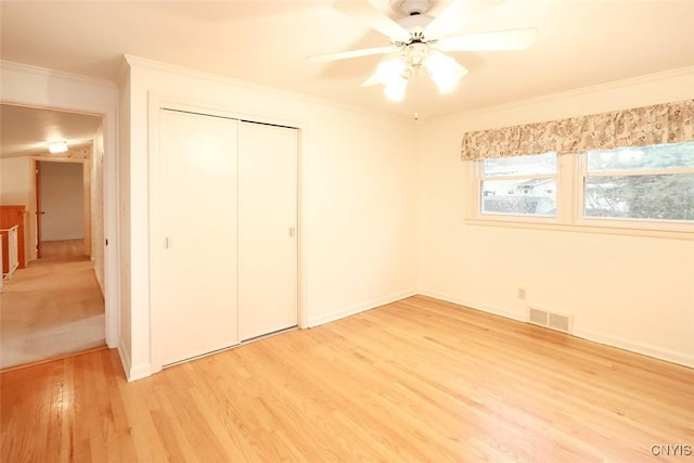 unfurnished bedroom with light wood-type flooring, a closet, crown molding, and ceiling fan