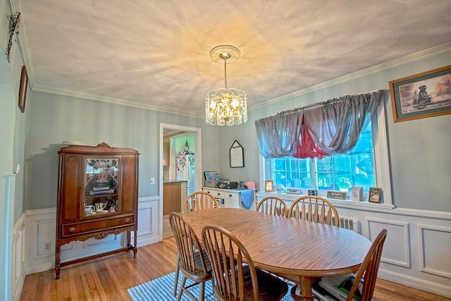 dining area with ornamental molding, light hardwood / wood-style flooring, and a chandelier