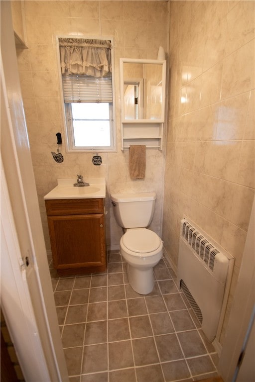 bathroom featuring vanity, radiator heating unit, toilet, and tile walls