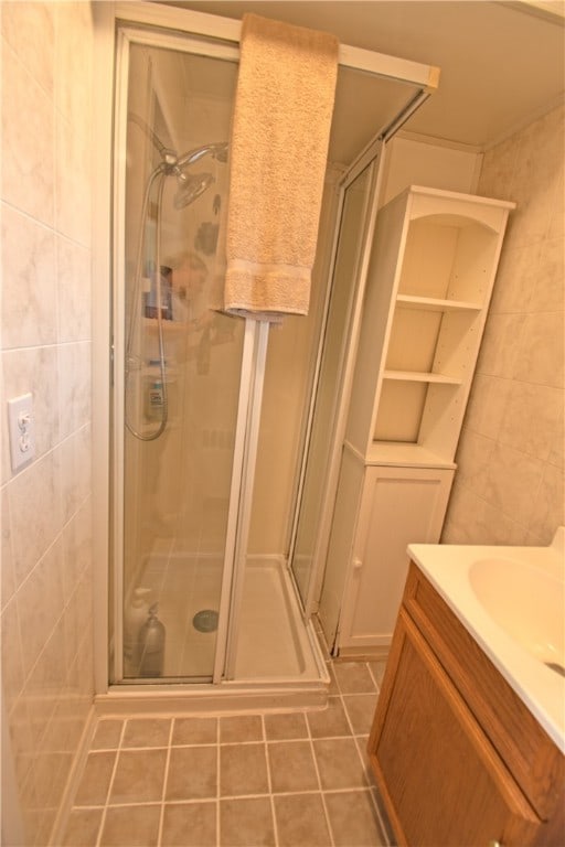 bathroom with vanity, tile patterned floors, a shower with door, and tile walls